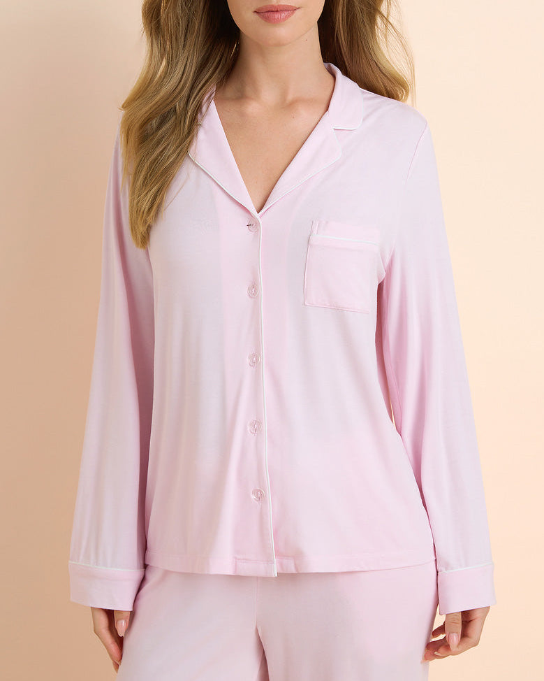 Woman wearing a light pink pajama set against a beige background